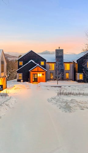 Stowe Woods exterior at dusk with snow-covered grounds and mountains in the background