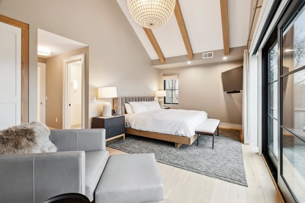 bedroom with vaulted ceiling, wood beams, king bed, and glass doors to the outside
